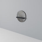 Oval konsthylla i svart finish, betongvägg